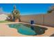 Kidney-shaped pool with a blue decorative pot set on a custom concrete patio and block wall in backyard at 4032 Rustic Oak Ct, North Las Vegas, NV 89032