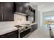 Kitchen with stainless steel range, hood, and dark cabinets; white countertops and backsplash, bright natural light at 472 Sand Dune Arch St, Las Vegas, NV 89138