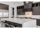 Close-up of kitchen island with seating, dark wood cabinets, stainless steel appliances and white countertops and backsplash at 472 Sand Dune Arch St, Las Vegas, NV 89138