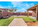 Large, private backyard with a stone pathway, well-manicured faux grass and a brick fire pit at 4932 Goldeneye Way, North Las Vegas, NV 89031