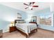 Bright blue bedroom with a dark wood frame bed, wood nightstands, and natural light streaming through the window at 5968 Saint Lazare St, Las Vegas, NV 89130