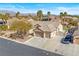 This is the front exterior of the home featuring a three-car garage, xeriscaping, and mature trees for shade at 5968 Saint Lazare St, Las Vegas, NV 89130