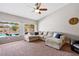 Bright living room with large windows overlooking pool, comfortable seating, and a ceiling fan at 5968 Saint Lazare St, Las Vegas, NV 89130