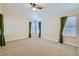 Spacious bedroom featuring neutral carpet, ceiling fan, and windows with decorative curtains at 6412 Yarmouth Dr, Las Vegas, NV 89108