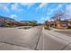 Exterior street view of the community entrance with sidewalks, desert landscaping, and sunny blue sky at 7083 Mackenzie Bay Ave, Las Vegas, NV 89179