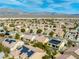 Expansive aerial view of a vibrant community with mountain views and homes with red tile roofs, many featuring solar panels at 7757 Coast Jay St, North Las Vegas, NV 89084