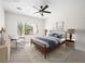 This staged bedroom features a large window, neutral carpet, a ceiling fan and modern furnishings at 7757 Coast Jay St, North Las Vegas, NV 89084