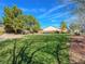 Well-manicured front yard with lush green grass and mature trees creating a serene landscape at 7757 Coast Jay St, North Las Vegas, NV 89084