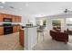 Bright kitchen featuring wood cabinets, black appliances, and an island with chairs and dining set, virtually staged at 7757 Coast Jay St, North Las Vegas, NV 89084