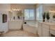 Well-lit bathroom featuring double sinks, a soaking tub, and ceramic tile floors at 7905 Brent Leaf Ave, Las Vegas, NV 89131