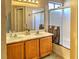 Bathroom featuring double sinks, wood cabinets, and a shower over bath with glass doors at 951 Carnival Ave, Las Vegas, NV 89123