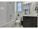 Modern bathroom with tiled shower and tub, bright window, and sleek vanity at 712 N Water St, Henderson, NV 89015