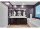 Stylish bathroom with a double sink vanity, large mirror, soaking tub, and wood-look flooring at 10184 Fire Skye Ave, Las Vegas, NV 89166