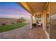 Covered brick patio with outdoor seating and a view of the landscaped backyard at 10184 Fire Skye Ave, Las Vegas, NV 89166