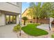 Serene backyard with lush artificial turf, putting green, desert landscaping, and covered patio with seating at 10644 San Vercelli Ct, Las Vegas, NV 89141