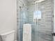 Modern tiled shower with blue accents, a glass door, and rounded window at 10644 San Vercelli Ct, Las Vegas, NV 89141