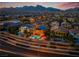 Sunset aerial view of a neighborhood featuring pools and solar panels with mountains in the background at 12279 Lost Treasure Ave, Las Vegas, NV 89138