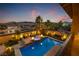 Beautiful pool with lounge seating, fire pits and desert landscaping, illuminated at dusk at 12279 Lost Treasure Ave, Las Vegas, NV 89138