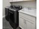 A functional laundry room with modern washer, dryer, sink and white cabinets at 12374 Skyracer Dr, Las Vegas, NV 89138