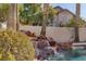 Beautiful pool area with a rock waterfall feature surrounded by lush greenery and a privacy wall at 2008 Arbor Forest St, Las Vegas, NV 89134