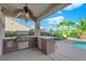 Outdoor kitchen area under covered patio, featuring a grill and bar seating by pool at 2244 Garden City Ave, Henderson, NV 89052