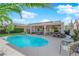 Relaxing backyard featuring a sparkling blue pool and covered patio with outdoor seating and lush greenery at 2244 Garden City Ave, Henderson, NV 89052