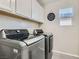 Well-equipped laundry room with modern washer and dryer units and overhead cabinets at 225 Sul Ponticello Ave, Las Vegas, NV 89011