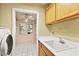 Bright laundry room with overhead storage and view to the front yard through shuttered windows at 255 El Camino Verde St, Henderson, NV 89074