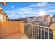 A balcony view featuring neighboring homes bathed in sunlight, under a bright blue, partly cloudy sky at 4228 Hickman Ct, Las Vegas, NV 89129