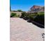 An interlocked brick-paved backyard featuring manicured bushes and flowering plants along the edges at 4562 White Cap Mill St, Las Vegas, NV 89147