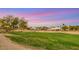 Golf course with green fairways and mature trees, surrounded by desert vegetation, under a colorful twilight sky at 4718 Atlantico St, Las Vegas, NV 89135