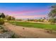 Scenic view of a well-manicured golf course with lush green grass and mature trees, set against a colorful twilight sky at 4718 Atlantico St, Las Vegas, NV 89135