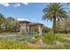 Community entrance with decorative stone and tiled roof, surrounded by lush landscaping and a tall palm tree at 5271 Villa Vecchio Ct, Las Vegas, NV 89141