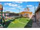 Spacious backyard with artificial turf, sun shade, trampoline, and lush landscaping at 5385 Ravendale Cir, Las Vegas, NV 89120