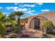 Close up of the home's front yard featuring a gated entrance, desert landscaping, and mature palms at 5385 Ravendale Cir, Las Vegas, NV 89120