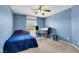 Blue bedroom with ceiling fan, window, work desk and comfortable bed at 5976 Ancona Dr, Las Vegas, NV 89141