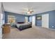 Inviting primary bedroom with a ceiling fan, carpet flooring, blue walls, and windows creating a relaxing atmosphere at 5976 Ancona Dr, Las Vegas, NV 89141