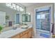 Bright bathroom with a single sink vanity, quartz countertops, and a tile shower with glass door at 5990 Mcleod Dr, Las Vegas, NV 89120