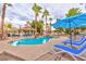 Backyard swimming pool and spa surrounded by lush landscaping, lounge chairs, and a covered outdoor kitchen and dining area at 5990 Mcleod Dr, Las Vegas, NV 89120