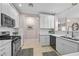 Well-lit kitchen features white cabinetry, stainless steel appliances, and neutral tile flooring with decorative rugs at 704 Peachy Canyon Cir # 101, Las Vegas, NV 89144