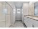 Bathroom featuring double sinks with granite counters, a glass-enclosed shower, and tile flooring at 7462 Dragonfruit Ave, Las Vegas, NV 89113