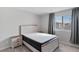 Bedroom with large window, neutral curtains, and a comfortable bed featuring wooden bed frame and neutral bedding at 7462 Dragonfruit Ave, Las Vegas, NV 89113