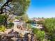 Lush backyard with a pool and stone waterfall feature, enhanced by mature trees and landscaping at 77 Chapman Heights St, Las Vegas, NV 89138