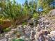 A serene backyard waterfall cascading over rocks, surrounded by trees and vegetation at 77 Chapman Heights St, Las Vegas, NV 89138