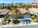 Charming single-story home featuring lush desert landscaping, a two-car garage and mountain views at 77 Chapman Heights St, Las Vegas, NV 89138