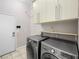 Modern laundry room with front loading washer and dryer, upper cabinets and tile floor at 77 Chapman Heights St, Las Vegas, NV 89138