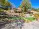 Landscaped backyard featuring a stone retaining wall and a green putting green in a serene setting at 77 Chapman Heights St, Las Vegas, NV 89138