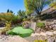 Manicured backyard with a built-in putting green, stone steps, and lush landscaping at 77 Chapman Heights St, Las Vegas, NV 89138