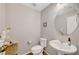 Half bathroom with a pedestal sink, toilet, and a round mirror at 7870 Formitch Ct, Las Vegas, NV 89166