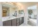 Bright bathroom with a double sink vanity, stylish mirrors, modern fixtures, and a view into bedroom at 8917 Pebble Sand St, Las Vegas, NV 89178